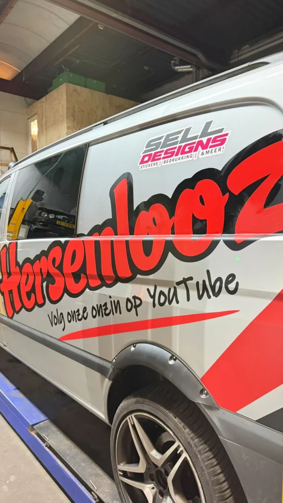 Rode en zwarte belettering op de zijkant van een witte bus