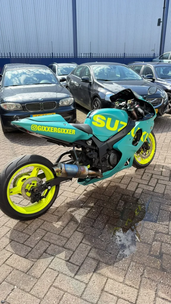 Turquoise motor met grote felgele belettering op de kuip, vanaf de zijkant