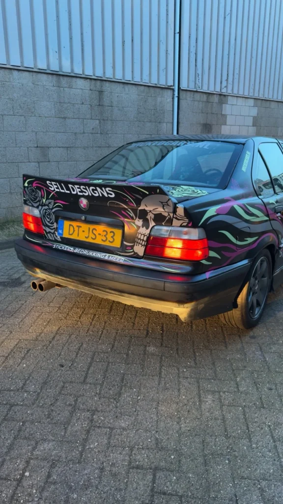 Achterkant van de Sell Designs-auto met doorlopende roze en groene bestickering