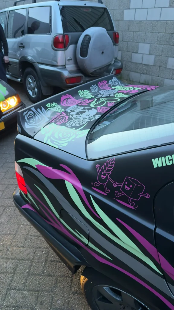 Roze en groene details van de bestickering bij de achterruit van de Sell Designs-auto