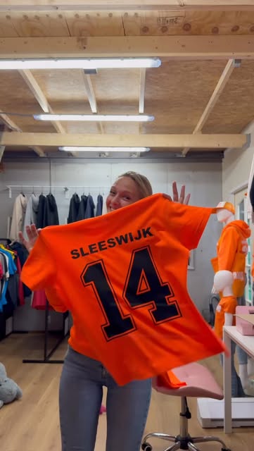 Selma toont een oranje shirt met naam en rugnummer 14