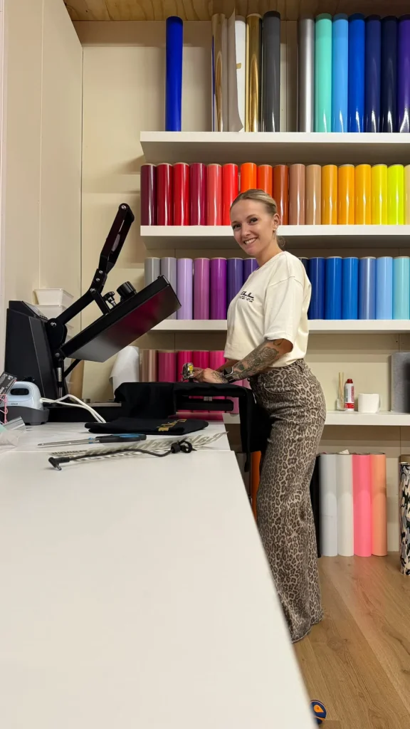 Selma staat bij de kledingpers in haar werkplaats