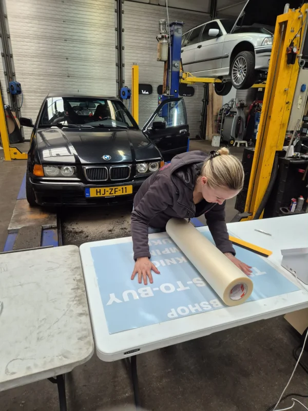 Selma bereidt uitgesneden voertuigbelettering voor op een werktafel